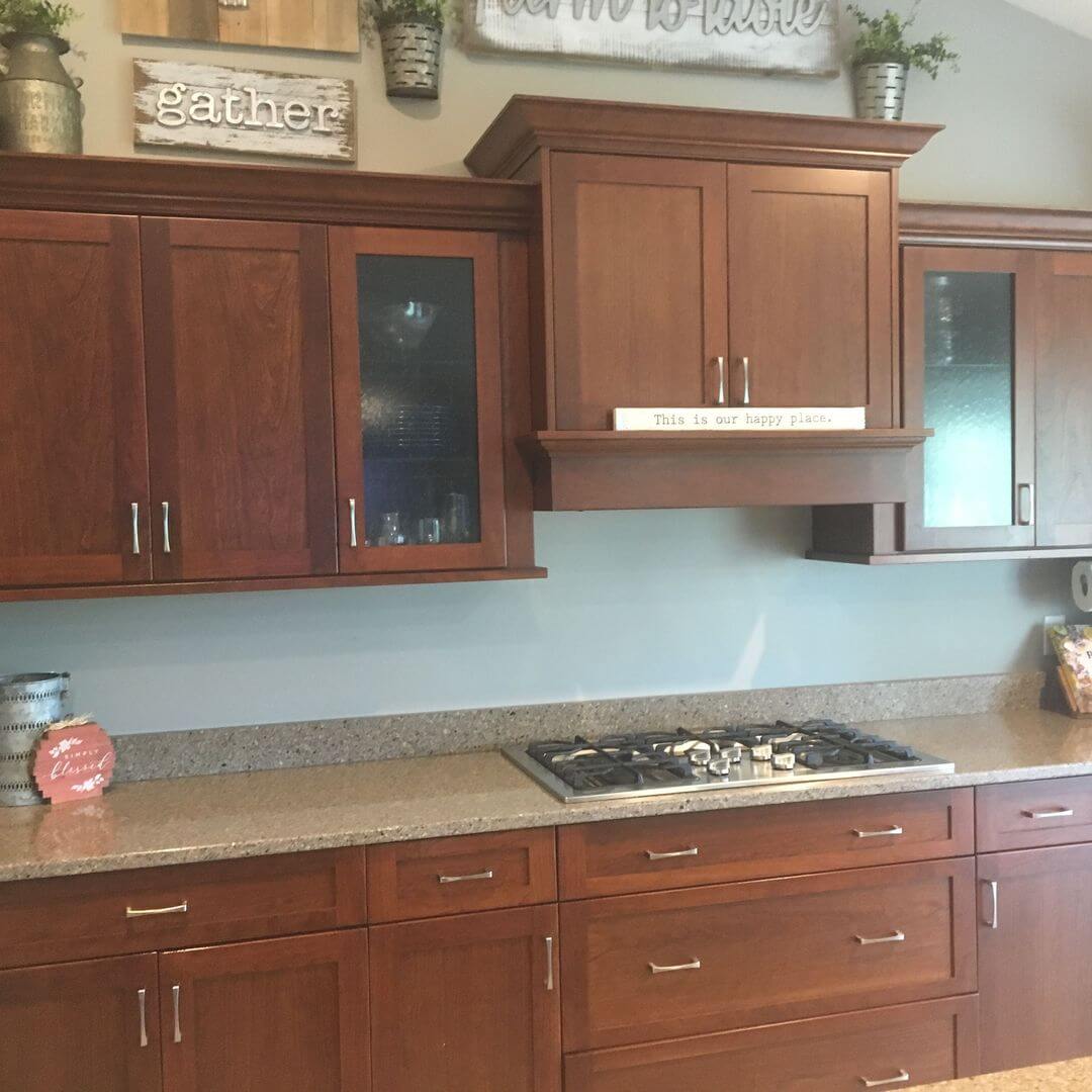Warm wood kitchen cabinets with glass inserts and a matching range hood